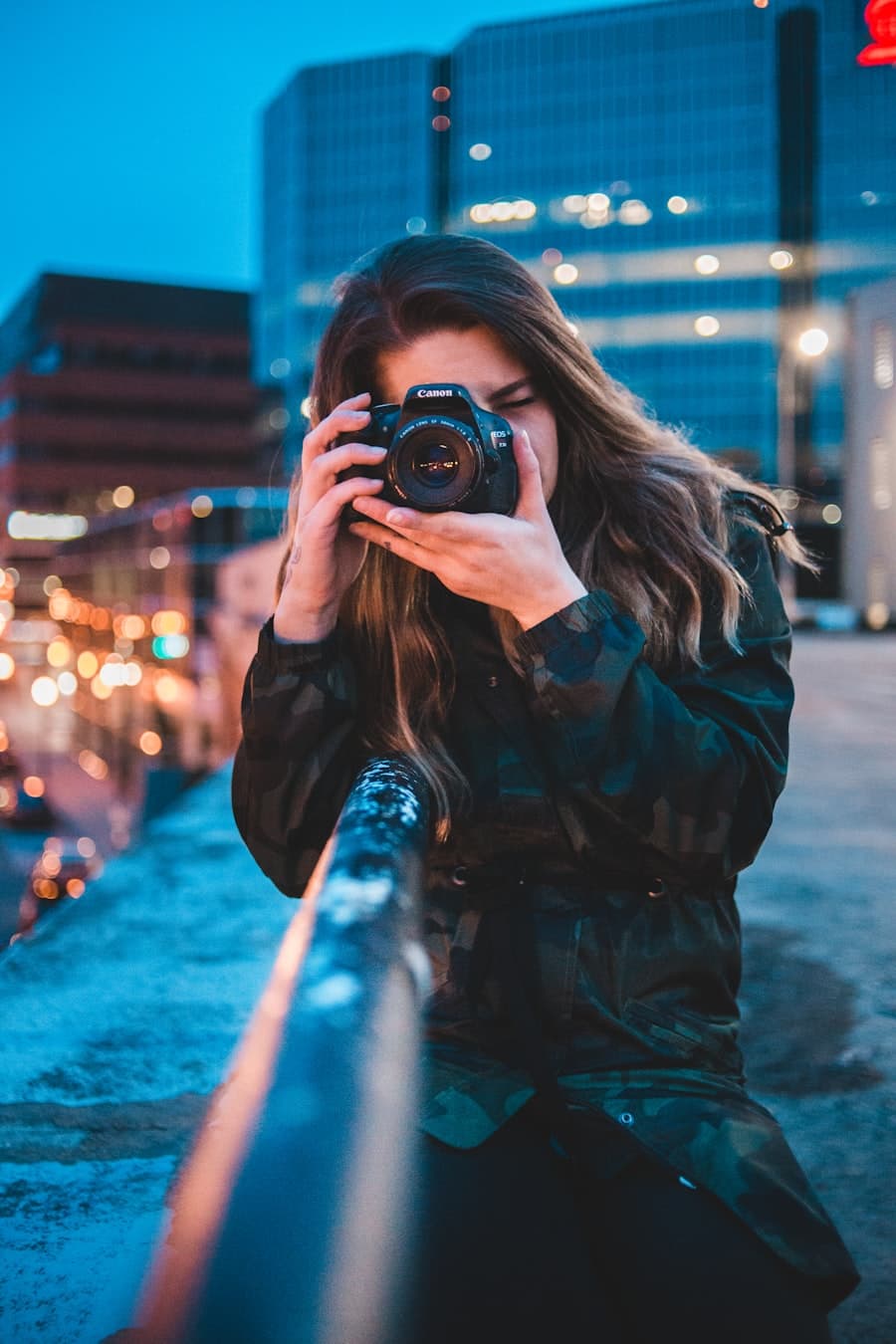 A photographer taking a photo at night with city lights in the background